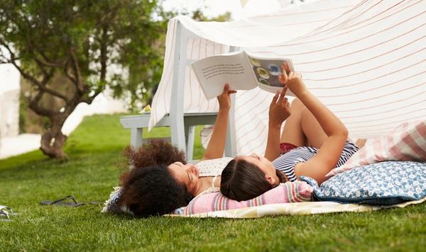 Image of mother and daughter reading outside together.