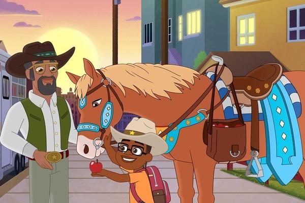 A cowboy stands with his horse and a child offers the horse an apple.