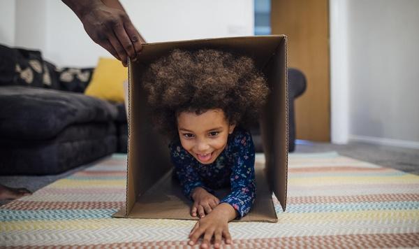 Child crawling through a cardboard box as part of an obstacle course.
