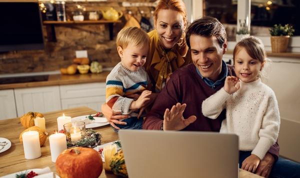 Family waving at laptop during dinner.