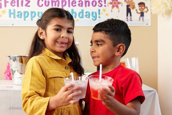 Two children holding cups of piragua-inspired punch.