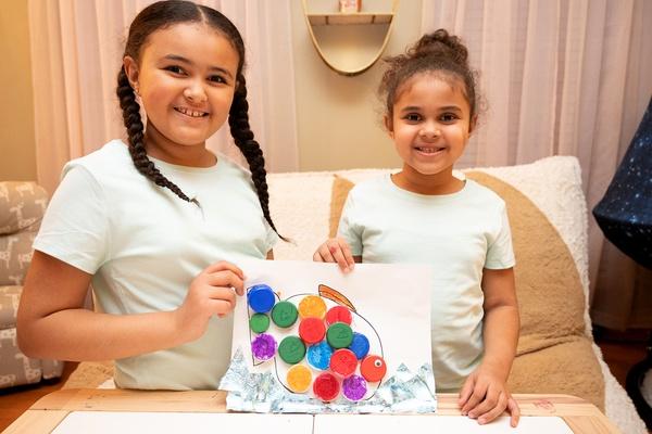Two sisters hold their favorite place portrait in honor of Earth Day.