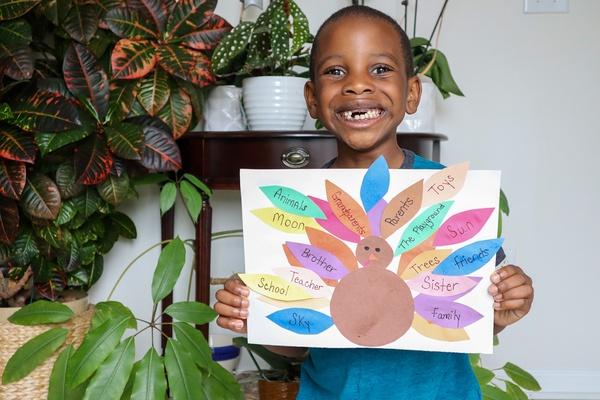 A child holds up their thankful turkey.