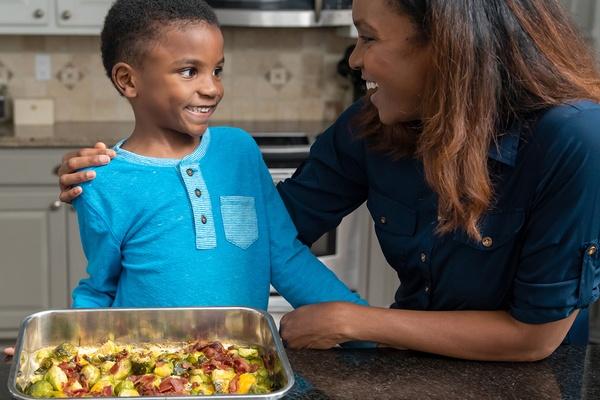 A parent and child celebrate making cheesy brussels sprouts together.