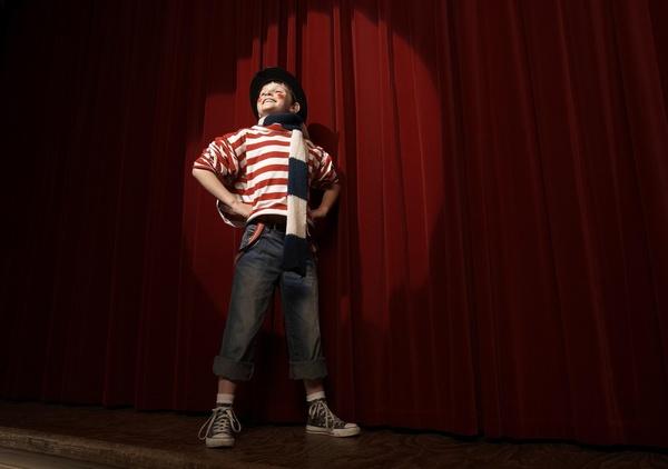 Child looking confident as they perform in the spotlight on a stage.