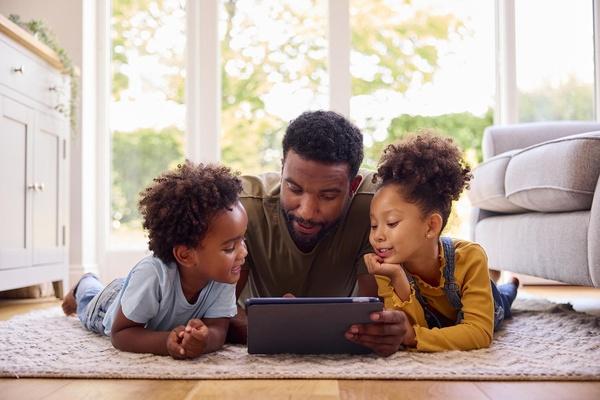 Kids and dad playing on tablet.