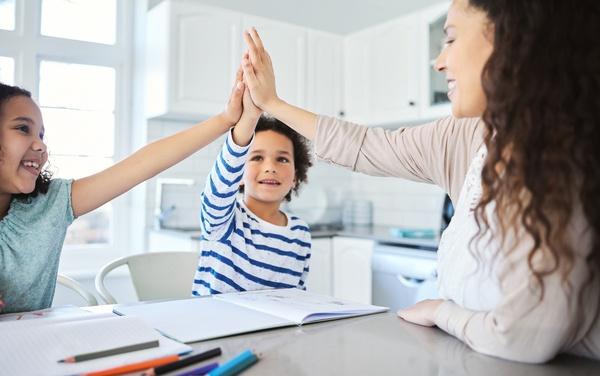 Una madre y dos niños chocan los cinco en grupo para celebrar un logro.