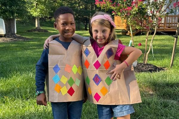 2 children stand together smiling while wearing their Carl the Collector argyle vests.