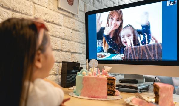 Image of young girl video chatting with family with birthday cake.