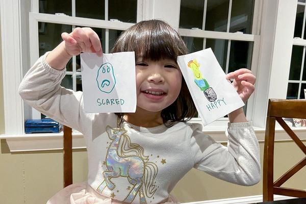 A child holds up pages from their Feeling Words Book