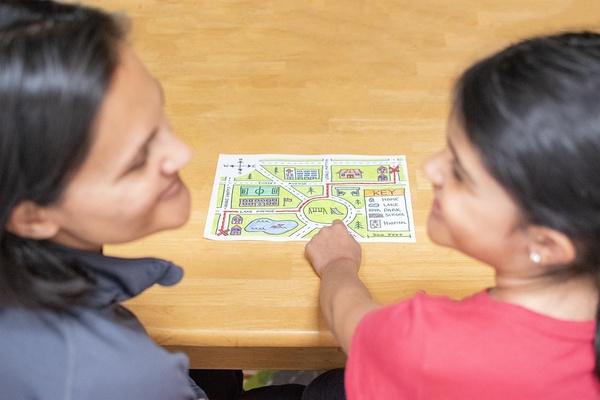 A parent and child share a story together about a trip they took while looking at a map.