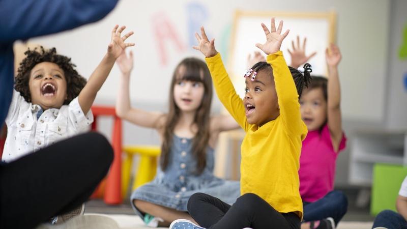 Grupo de niños levantando la mano en clase.