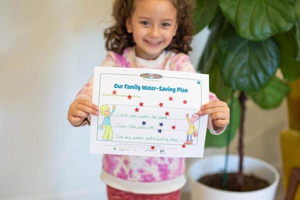 Girl holds her completed family water conservation plan.