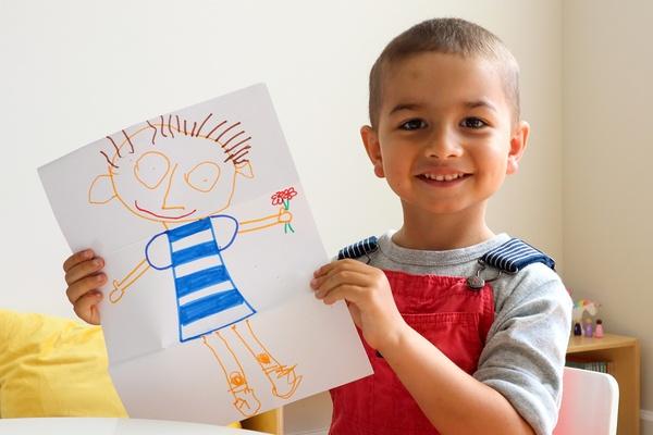 A child holds his silly folded picture up.