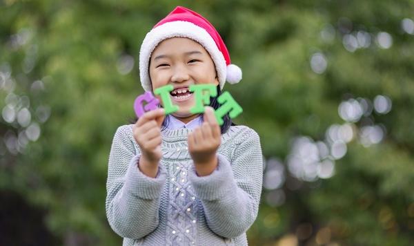 A child wearing a Santa hat holds the letters G-I-F-T.