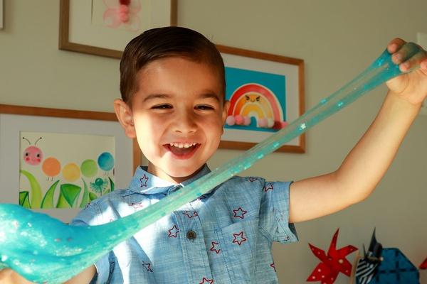 A child holds up their 4th of July slime.