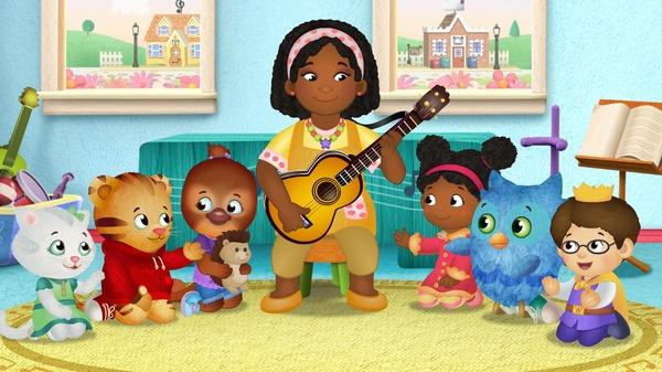 Teacher Harriet plays a guitar and sings songs with her students.