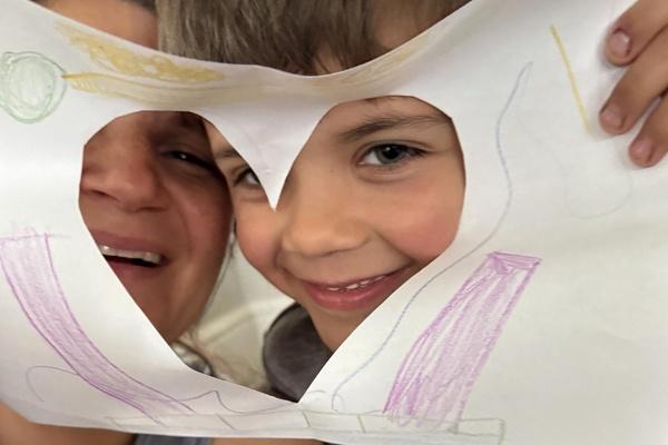 A parent and child frame themselves with a heart cut out.