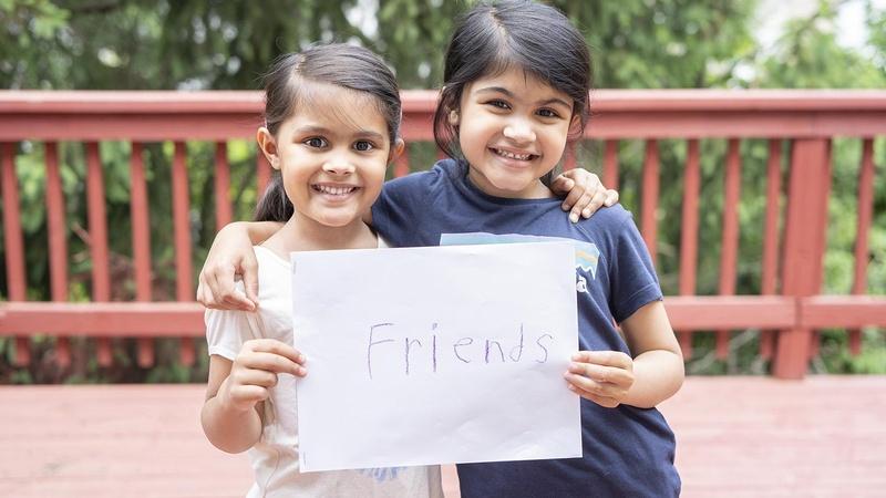 Two friends hold their book together.