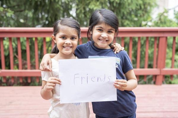 Two friends hold their book together.