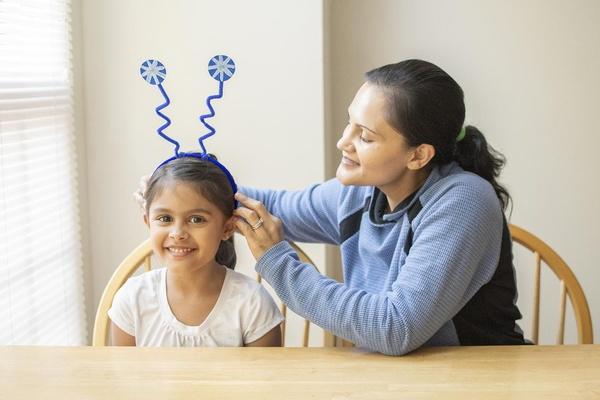 A parent places the snowflake costume headband on their child's head.