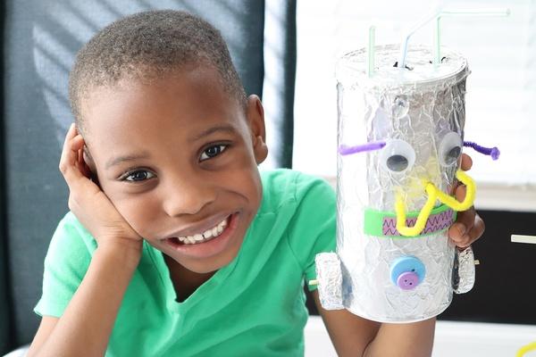 Un niño sostiene su creación artística hecha con materiales reciclados.