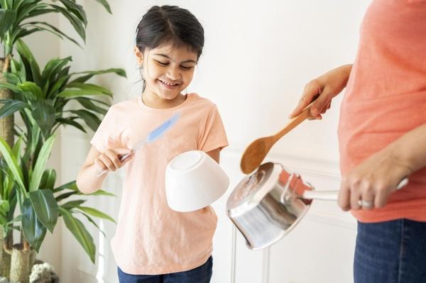 A daughter bangs on a bowl with a wooden spoon.