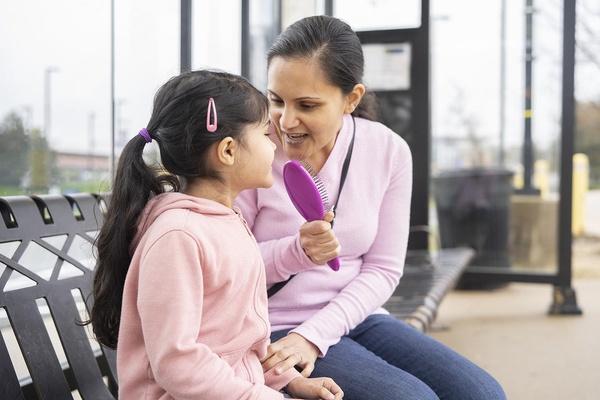 Una mamá y su hija cantan juntas mientras esperan.