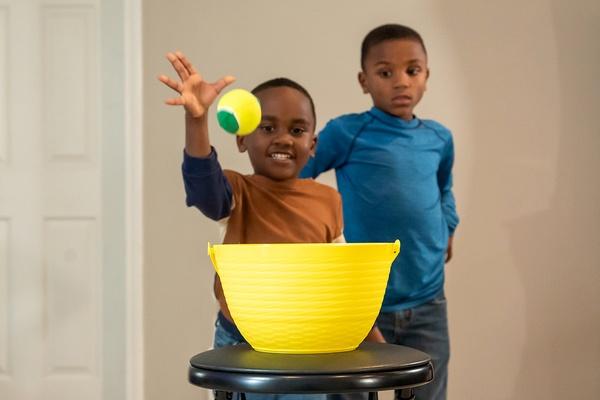 Child throwing a ball in a basket.