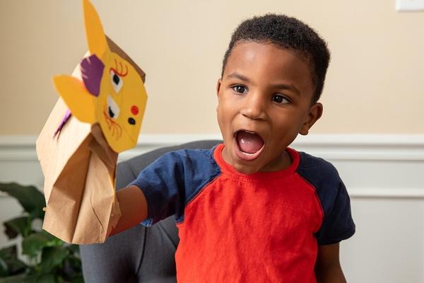A boy plays with his Donkey Hodie puppet.