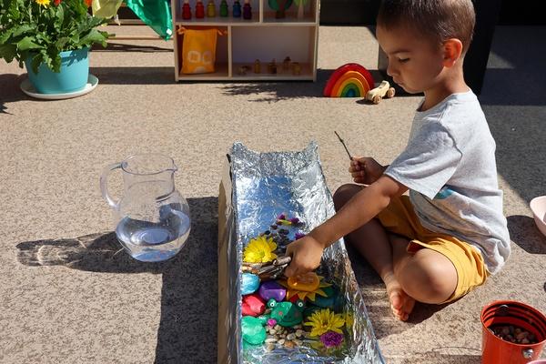 A child places objects in a model river to try to change the flow of the water.
