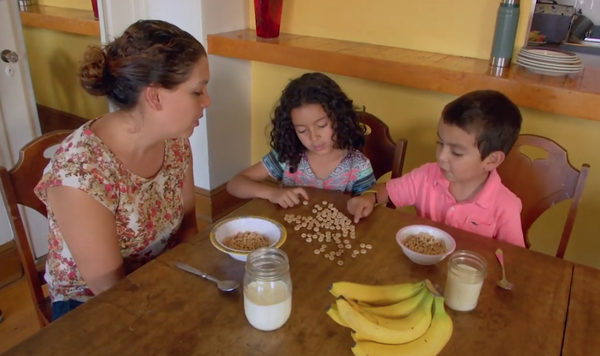 Image of mom with two kids who are practicing counting with cereal.
