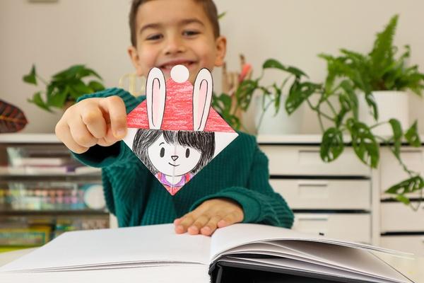 A child holds a finished corner bookmark.