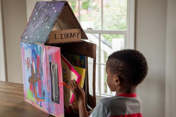Child taking a book from the mini library.