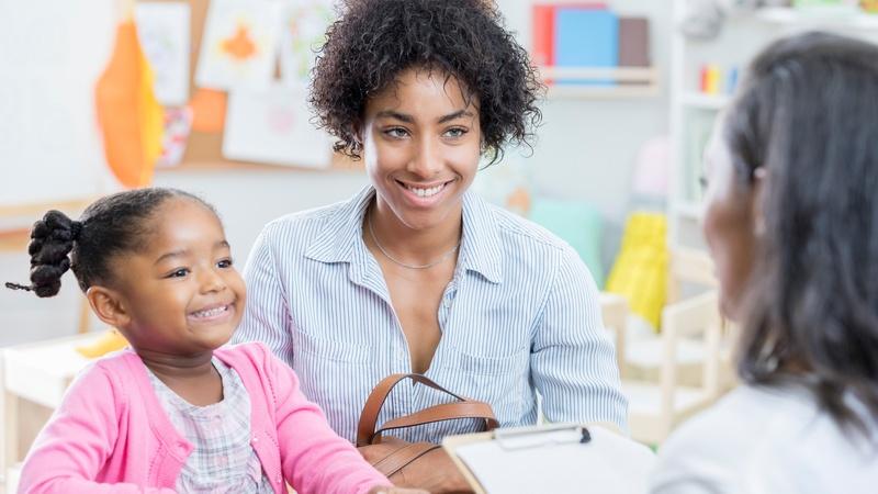 Una mamá y su hija se reúnen con la maestra en la escuela.