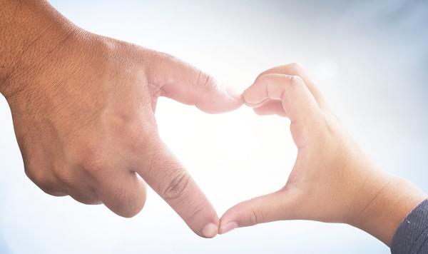 Parent and child forming a heart with their hands.