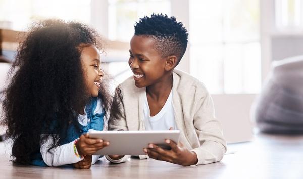 A boy and girl playing on a tablet.