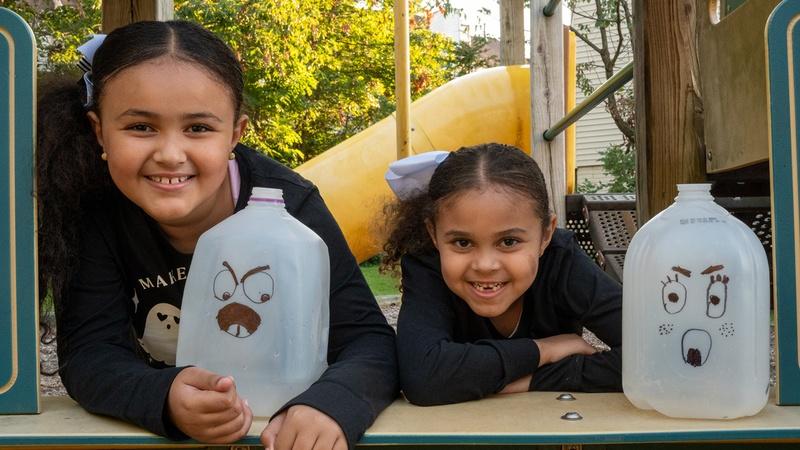 Two girls hold their glowing ghost jugs.