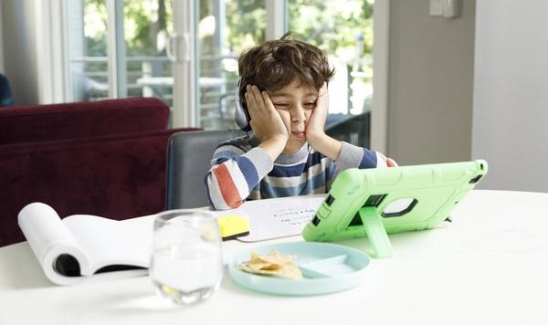Young boy frustrated while looking at a tablet.