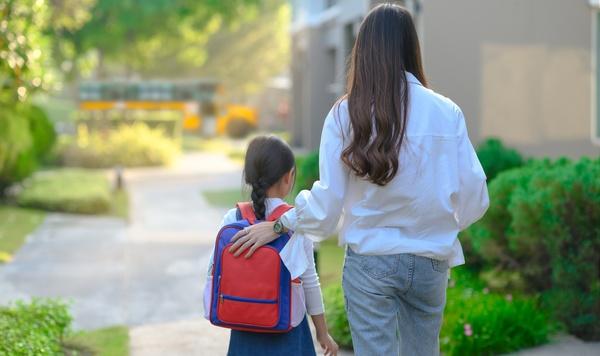 Mom walking her daughter to school.