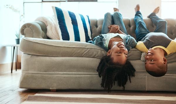 Brother and sister hanging upside down off the couch.
