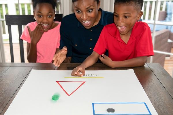 A parent and two children play lidtop slide.