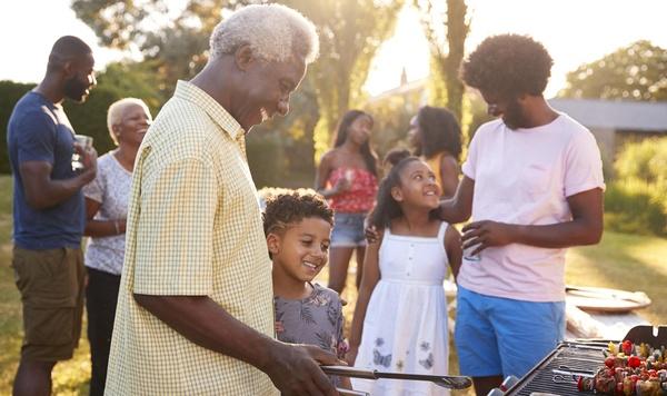 Grandfather and grandson grilling food at a family barbecue.