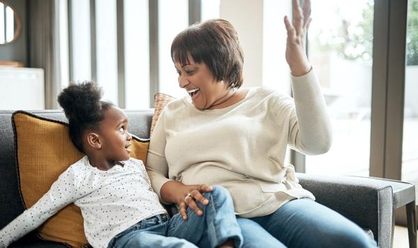Grandmother and granddaughter sitting on the couch talking.
