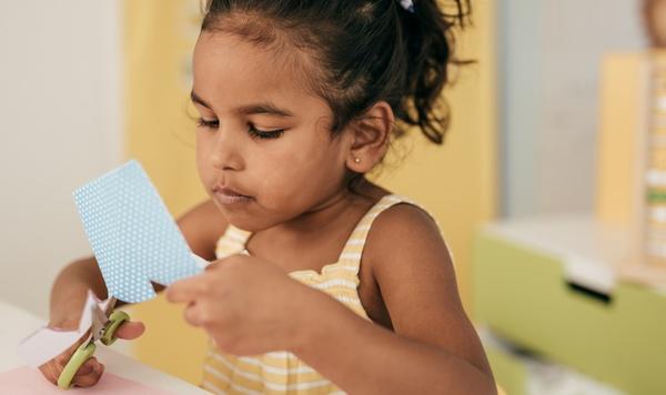 Young girl using scissors.