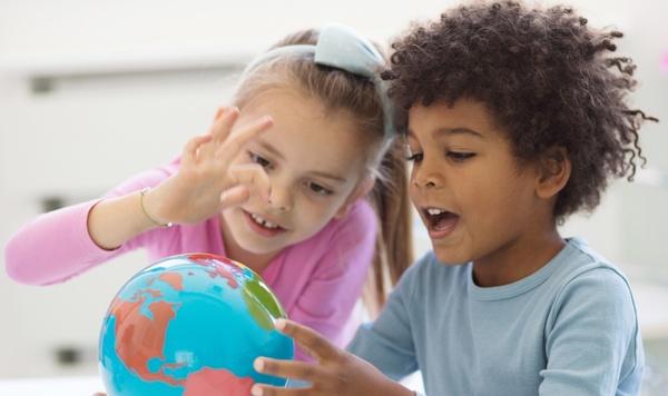 Two children looking and pointing at a globe.