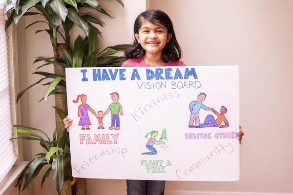A child holds her finished Martin Luther King Jr. activity, an "I Have a Dream" vision board.