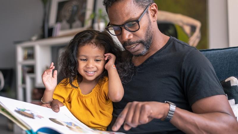 Father and child read a book together.
