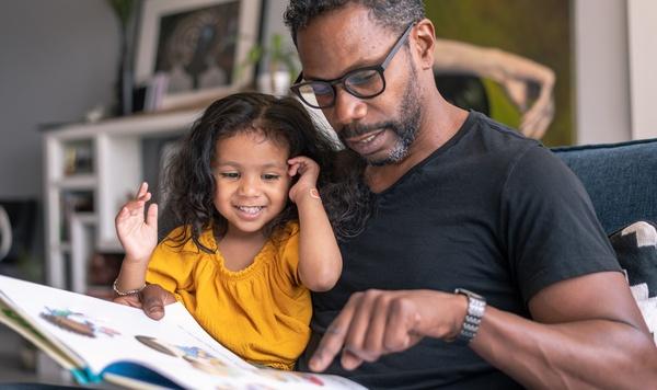 Father and daughter reading a book together.