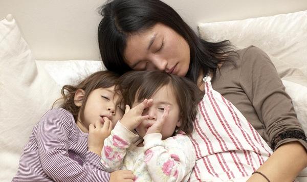 Mother takes a nap with her two daughters.